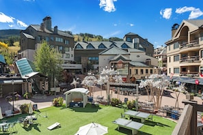 A hotel courtyard with outdoor seating, a stage, and a view of surrounding buildings. - Ski-in/out 4BR Beaver Creek condo with mountain views. (Beaver Creek)