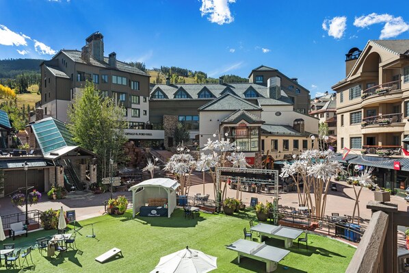 A hotel courtyard with outdoor seating, a stage, and a view of surrounding buildings.