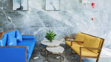 Una habitación con un sofá azul, un sillón amarillo y una mesita con una planta.