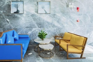 A room with a blue sofa, a yellow armchair, and a small table with a plant. - Xingzhike Hotel (Wuchuan)