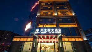 A modern hotel building with illuminated signage and large windows. - Xingzhike Hotel (Wuchuan)