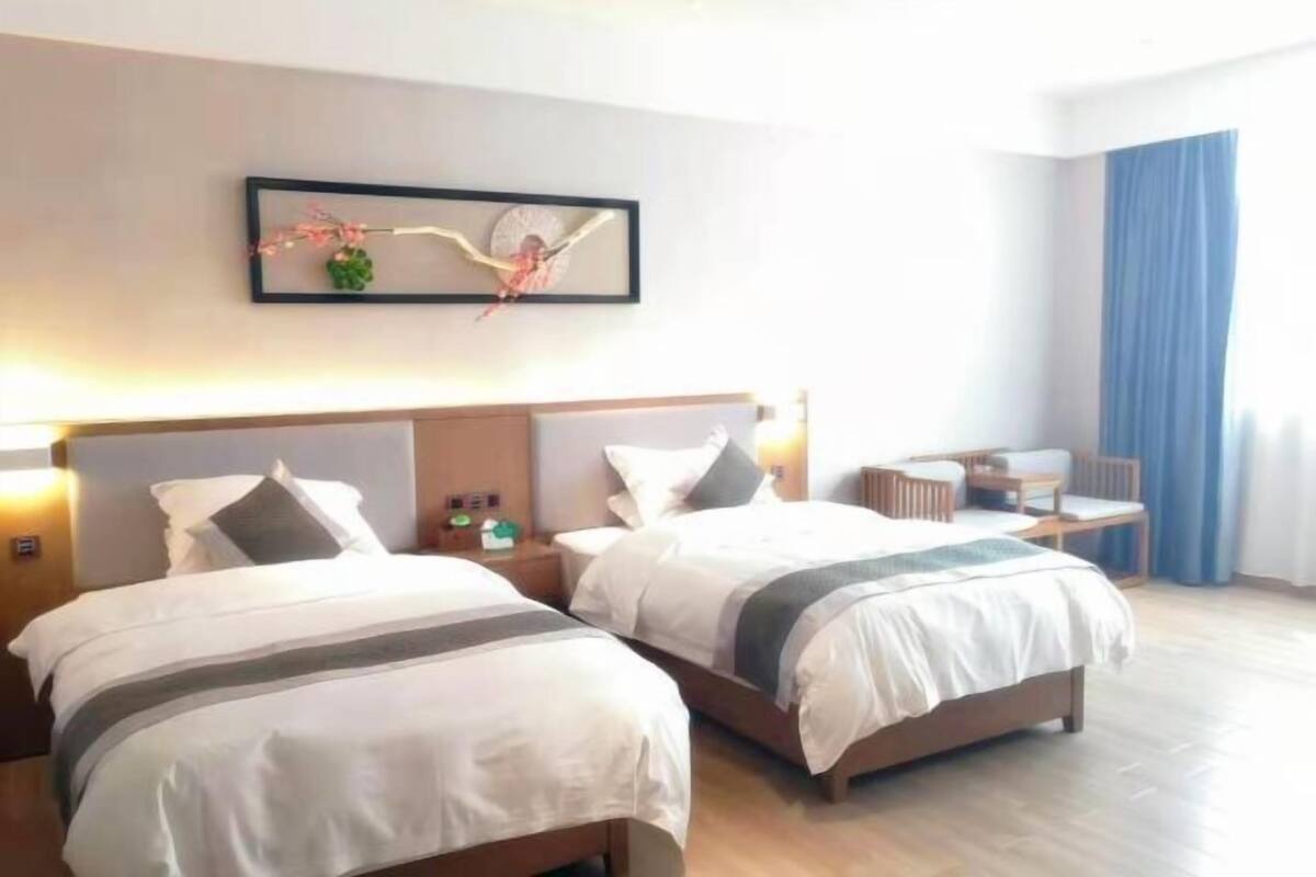 A hotel room with two beds, a desk, and a chair.