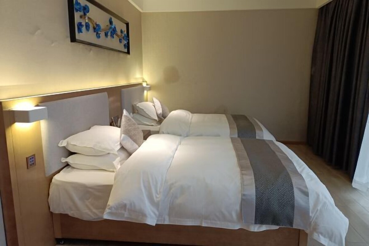 Una habitación de hotel con una cama grande, una mesita de noche, una lámpara y un cuadro en la pared.