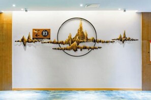 A wall with a circular artwork and a directional sign. - Xingzhike Hotel (Wuchuan)