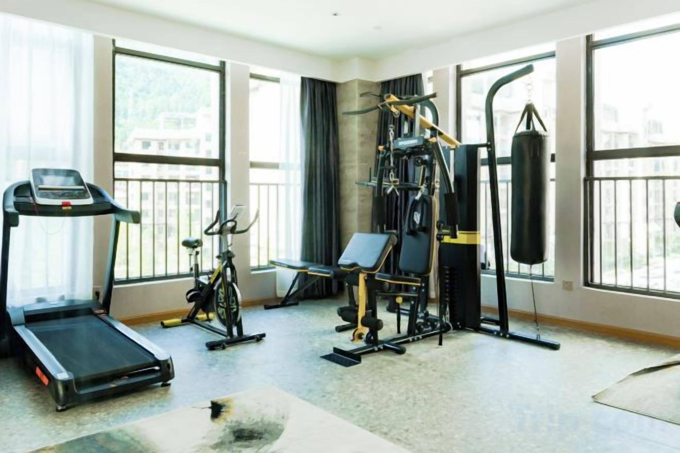 Un gimnasio con cinta de correr, bicicleta estática y equipo de levantamiento de pesas.