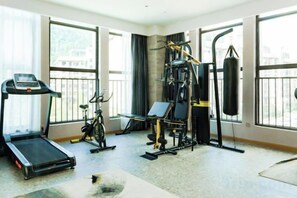 Un gimnasio con cinta de correr, bicicleta estática y equipo de levantamiento de pesas.