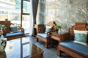 A traditional-style room with wooden furniture, a glass table, and a view of the street outside. - Xingzhike Hotel (Wuchuan)