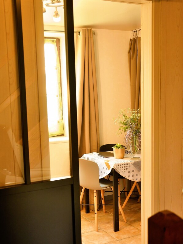 A dining area with a table set for two, a chair, and a potted plant.