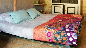 A bedroom with a bed, a dresser, a wall clock, and a decorative shelf.