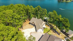 Une propriété au bord du lac comprenant une grande maison, un quai et un bateau.