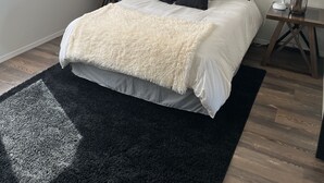Ein Schlafzimmer mit einem Bett, einer Schwarzweiß-Grafik, einer Lampe und einem kleinen Tisch.