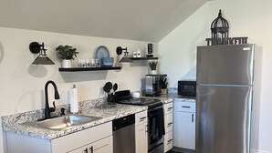 Eine moderne Küche mit weißen Schränken, einem Edelstahlkühlschrank, einem Geschirrspüler und einer schwarzen Arbeitsplatte.