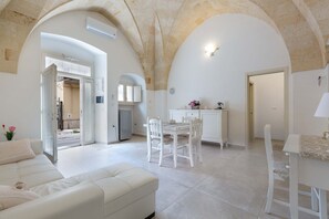 Amplia sala de estar con una mesa de comedor y sillas, un sofá y una cocina integrada con nevera y armarios.
