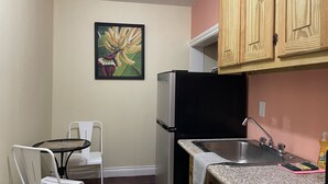 Uma cozinha compacta com geladeira, pia e uma área de jantar com cadeira e mesa.