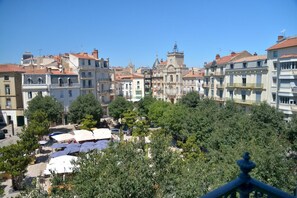 A view of a cityscape with historic buildings, trees, and outdoor seating areas.