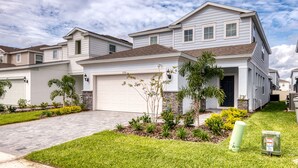 A two-story residential house with a garage, a driveway, and a well-maintained lawn.