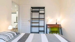 Un dormitori amb un llit, escriptori, cadira i estanteria.