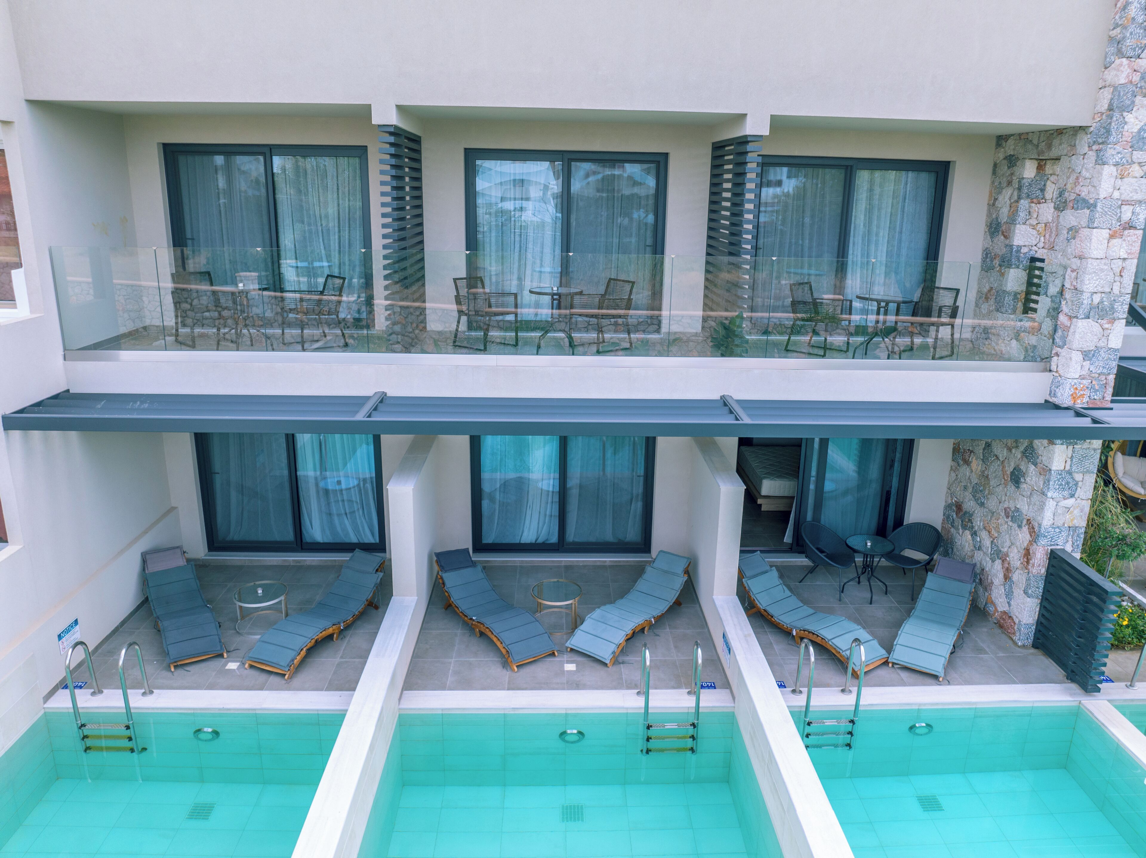 Ein modernes Hotel mit Poolbereich auf dem Dach, ausgestattet mit Liegestühlen und einem Glasgeländer.