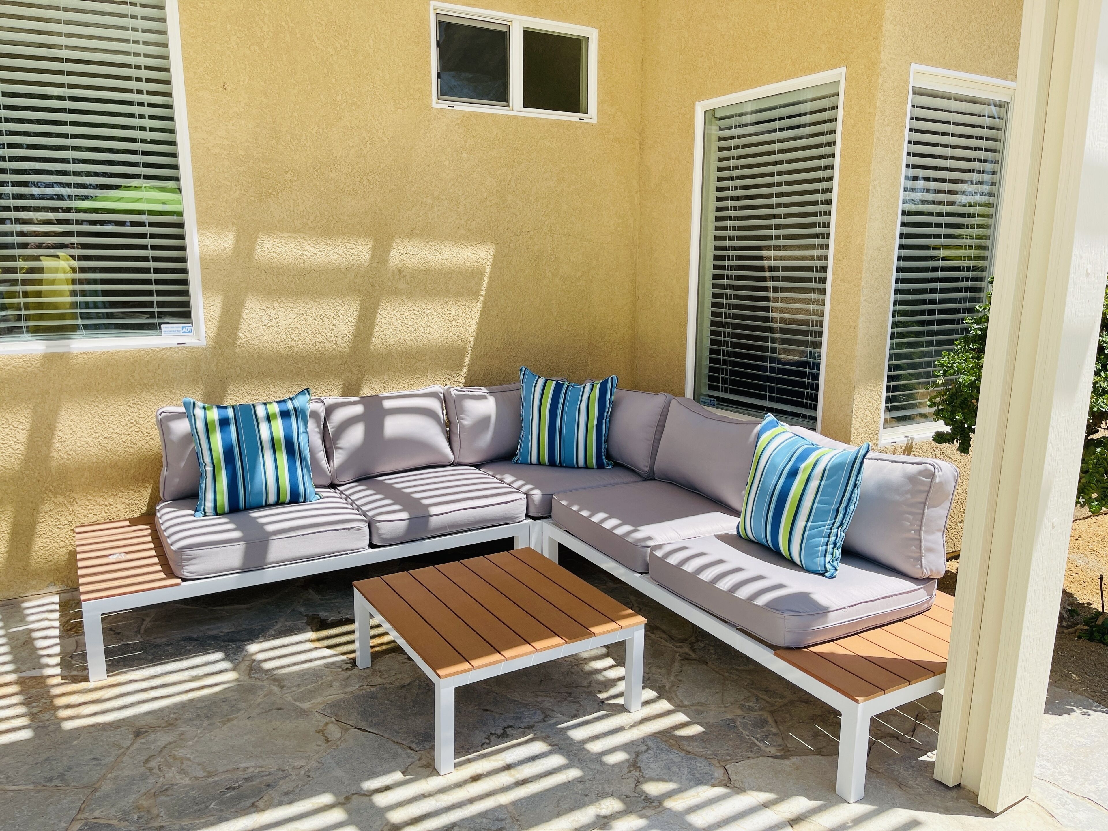 A beige exterior wall with a gray sectional sofa and a wooden coffee table.