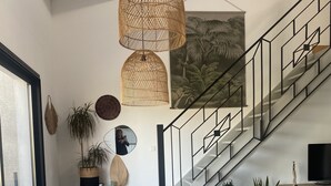 A modern dining area with a large wooden table, chairs, and a hanging woven light fixture. - Villa Tout Confort Entre MER ET Etang (Sète)