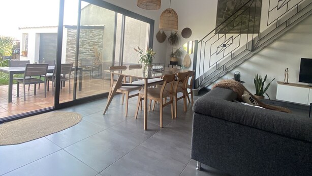 A spacious living area with a dining table, chairs, a sofa, and a staircase. - Villa Tout Confort Entre MER ET Etang (Sète)