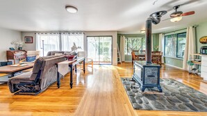 Un salon spacieux doté d’un plancher en bois, d’une cheminée en pierre et d’un coin repas avec une table et des chaises.