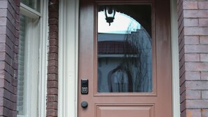 A red door with a white frame, a small window to the left, and a black doorbell. - Beautiful 4bd, 2.5ba Lancaster Center City Townhome (Lancaster)