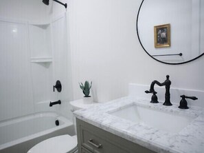 A bathroom with a white bathtub, a marble sink, and a small potted plant. - Beautiful 4bd, 2.5ba Lancaster Center City Townhome (Lancaster)