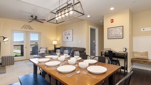A dining area with a wooden table set for four, a ceiling fan, and a view of the mountains through the sliding glass doors. - Pool & Pedals Biking Base at Granby Ranch (Granby)