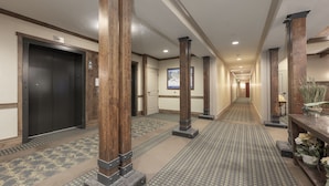 A hotel corridor with wooden pillars, a patterned carpet, and a door with a sign. - Pool & Pedals Biking Base at Granby Ranch (Granby)