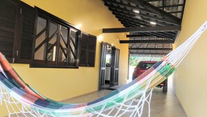A hallway with a hammock, wooden shutters, and a car parked outside. - House with pool Guaratuba-Barra do Saí - 100 m from the beach (Guaratuba)