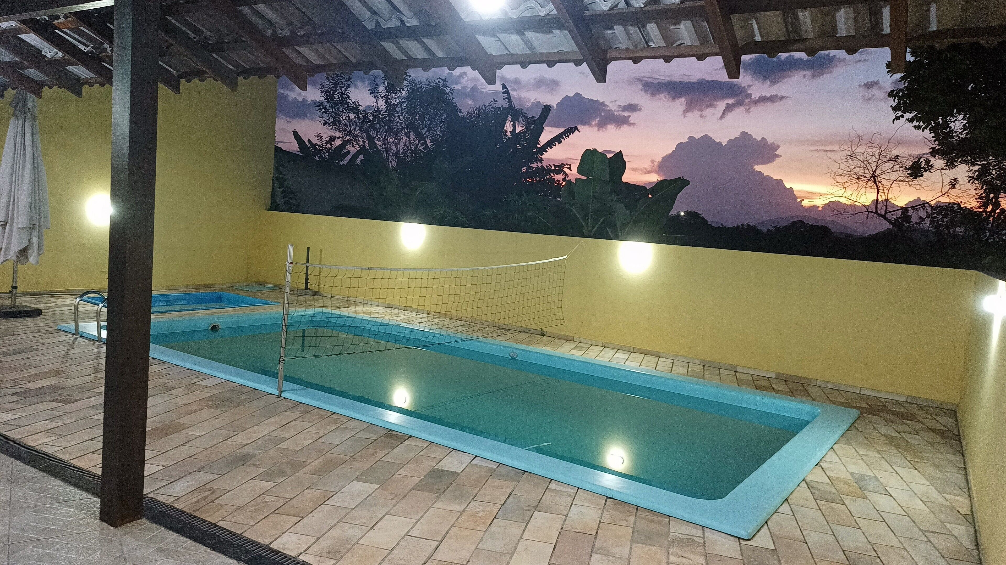 An indoor swimming pool with a net, tiled floor, and a mural of a sunset.