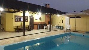 An outdoor pool area with a covered seating area, a small bar, and a poolside chair. - House with pool Guaratuba-Barra do Saí - 100 m from the beach (Guaratuba)