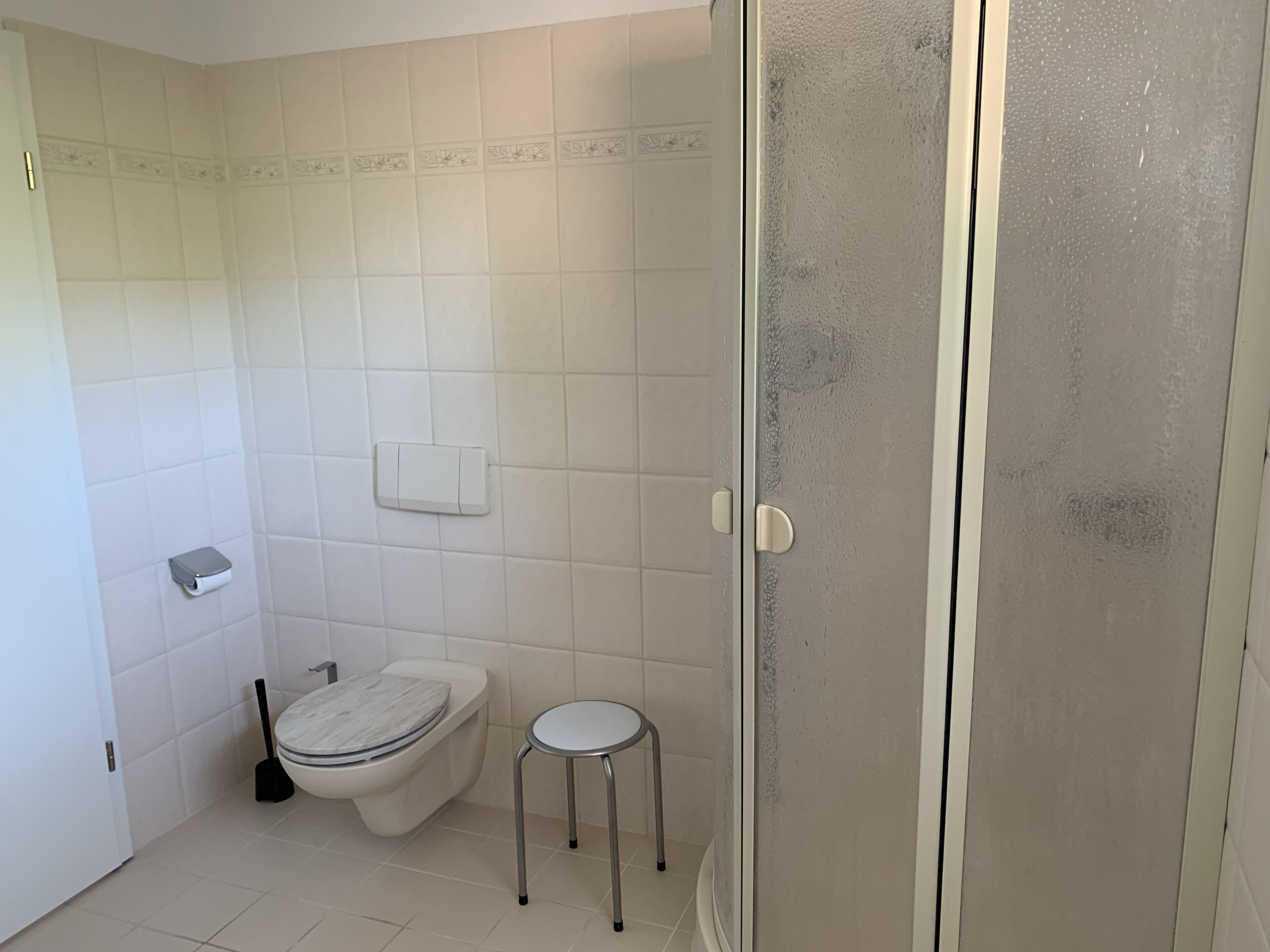 A bathroom with a toilet, bidet, and a small stool.