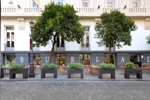 Ein Restaurant mit Außenbereich, großen Fenstern und einer von Bäumen gesäumten Fassade.
