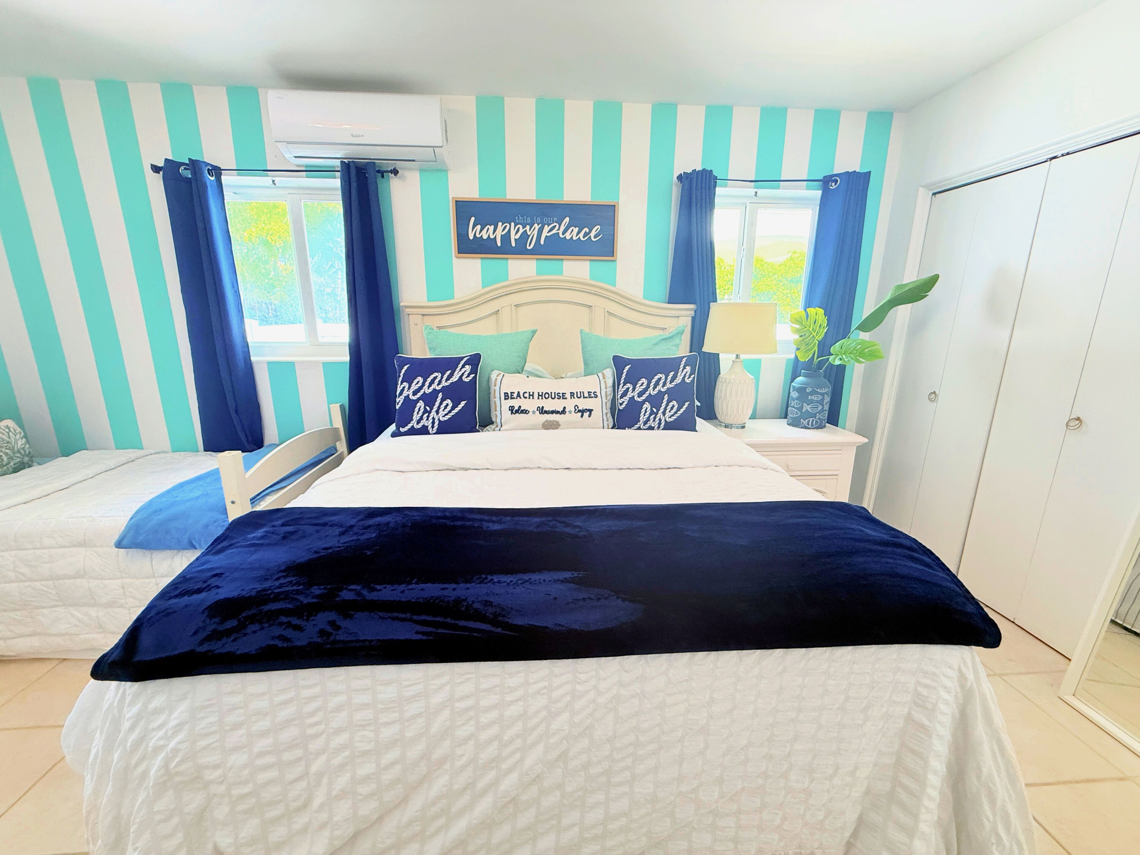 A bedroom with a bed, a nightstand, a lamp, and a sign that says "happyplace".