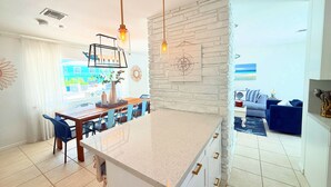A modern kitchen with a large island, white cabinetry, and a stone accent wall. - Casa Azul, Key Largo, Home w Private Pool & Dock (Key Largo)
