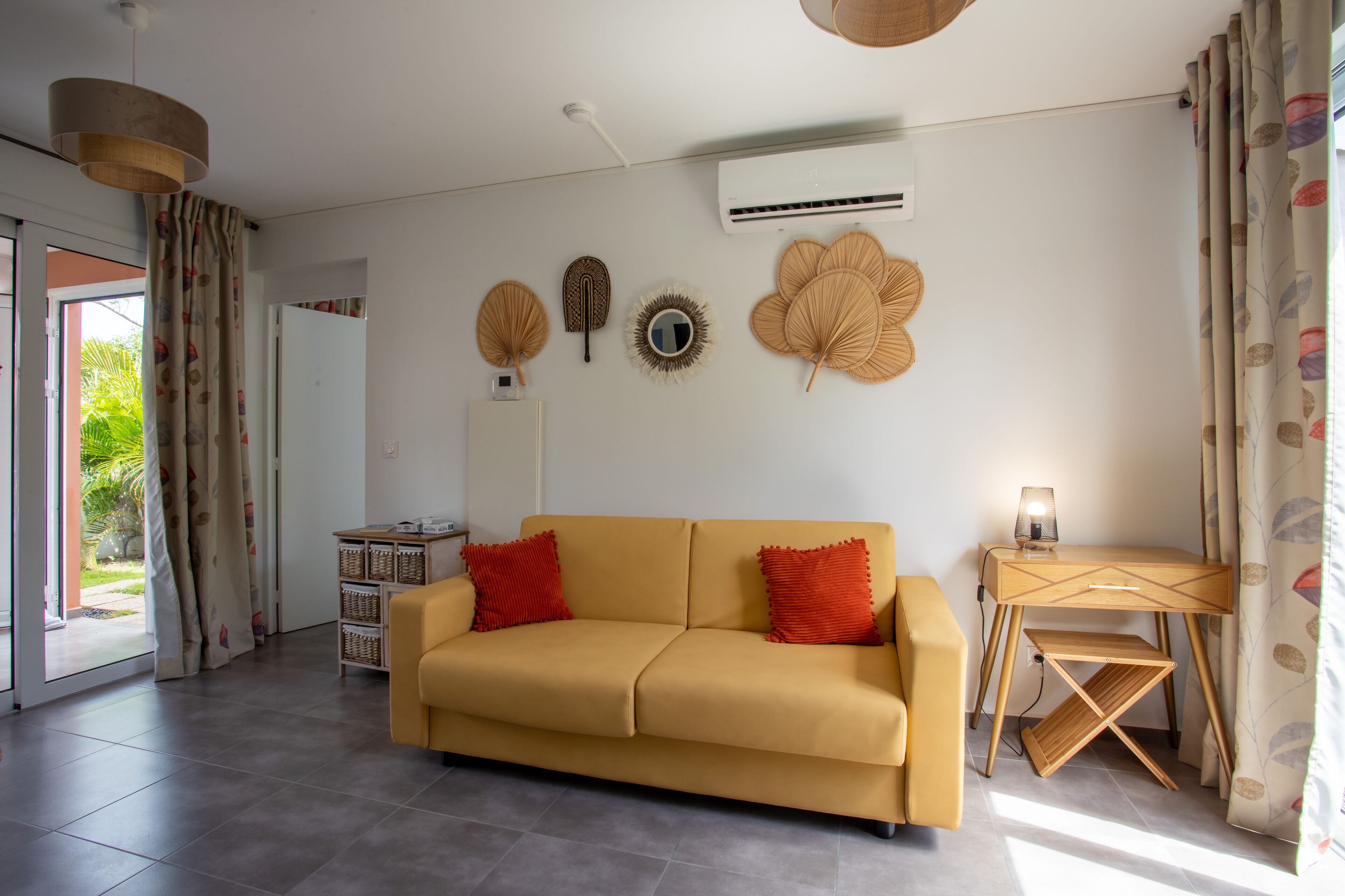 A modern living room with a sofa, a desk, and decorative wall hangings.