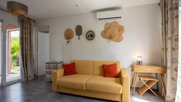 A modern living room with a sofa, a desk, and decorative wall hangings.