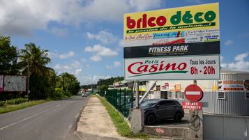 A road sign for Brico Deco, a fitness park, and Petit Casino with operating hours.