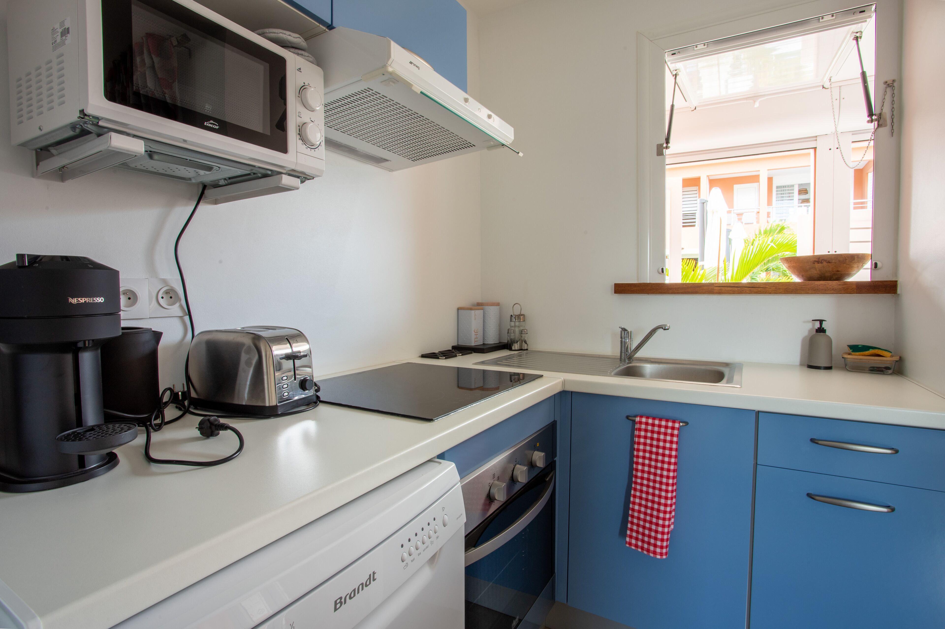Une cuisine compacte équipée d’un four à micro-ondes, d’un grille-pain, d’une machine à café et d’un lave-vaisselle.