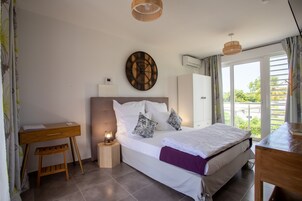 A bedroom with a bed, bedside table, desk, and a wall clock.