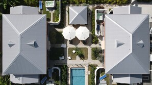 A rooftop pool area with two large umbrellas, a hot tub, and a rectangular pool. - Hôtel Guadeloupe Palm Suites (Saint-François)