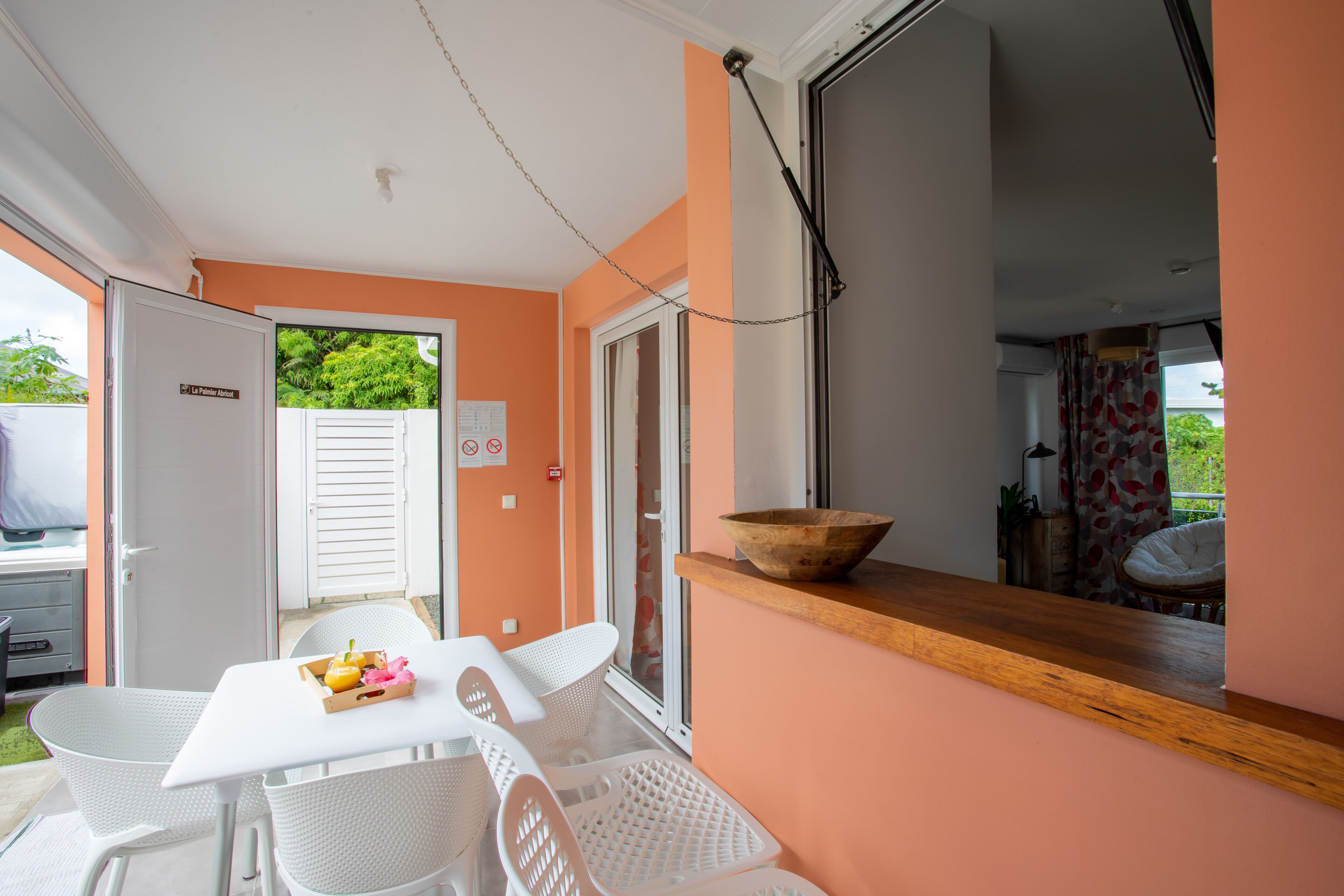 A kitchen area with a wooden countertop, a white table with chairs, and a view of the outside.