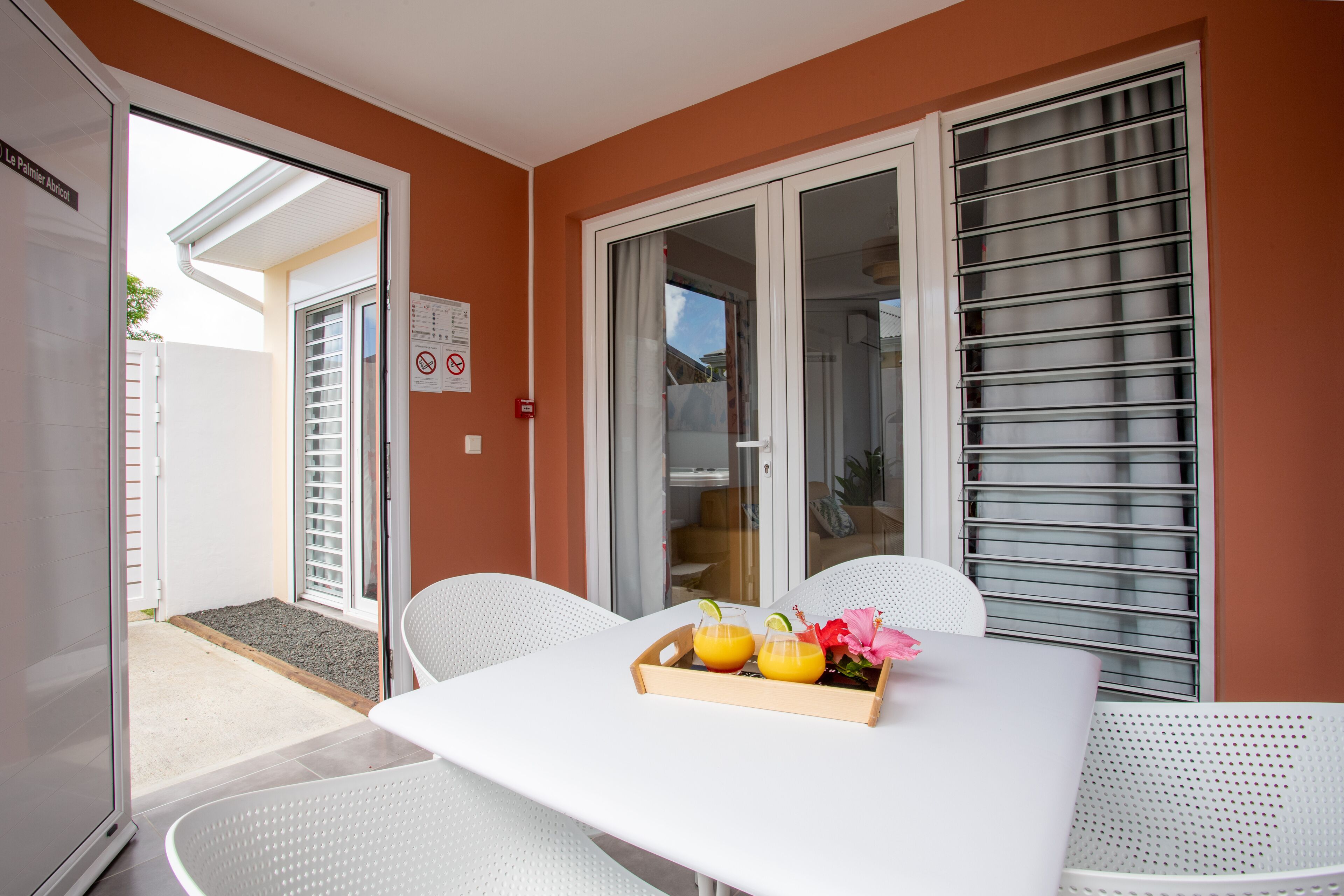 Un coin repas avec une table dressée pour deux personnes, agrémenté d’un plateau sur lequel se trouvent deux boissons et une fleur.