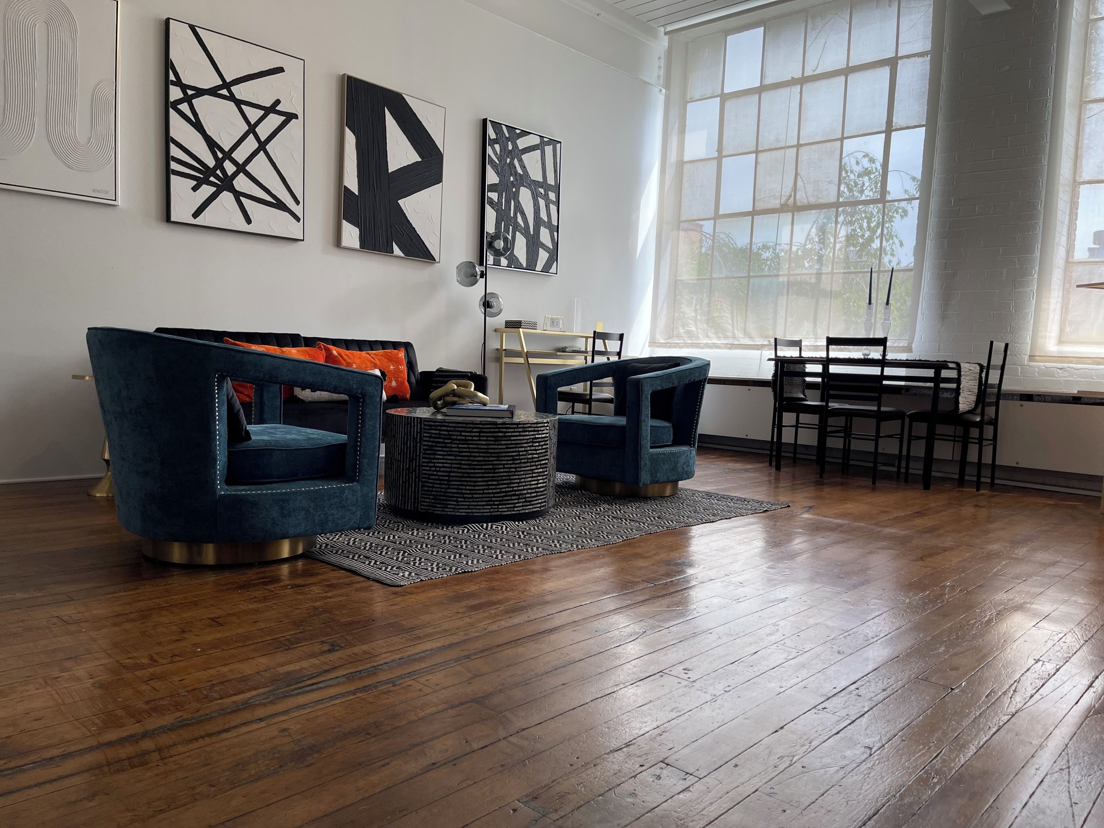 A modern living room with a dark blue sofa, two armchairs, a coffee table, and a dining area with a table and chairs.