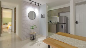 Una cocina moderna con un refrigerador de acero inoxidable, armarios de madera y una pared decorativa de ladrillo blanco.