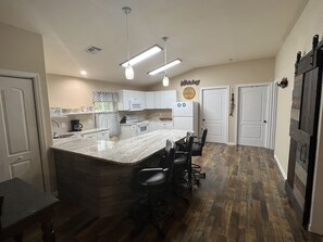 Una cocina moderna con una isla grande, armarios blancos y piso de madera.
