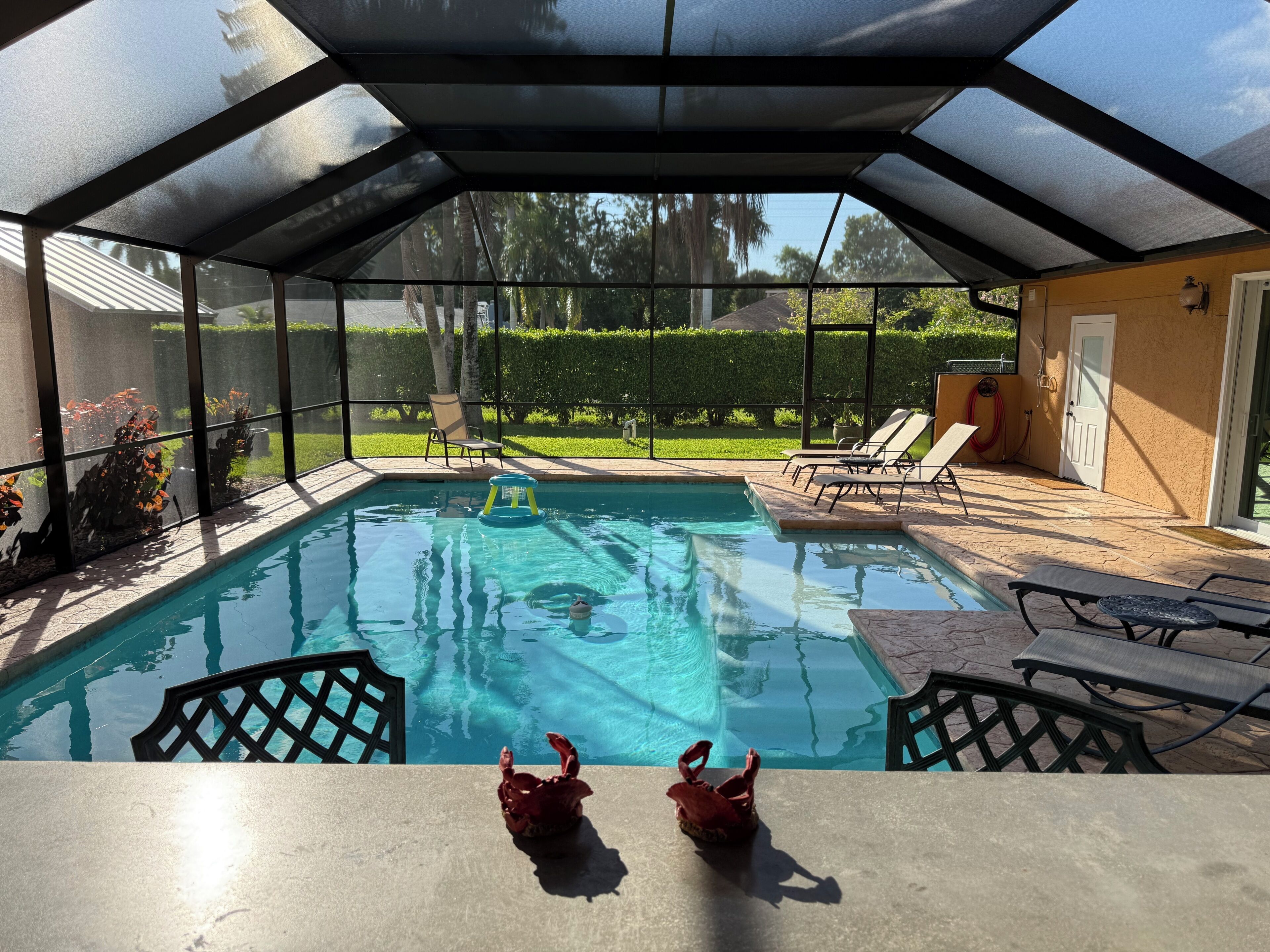 A covered outdoor swimming pool with lounge chairs and a table.