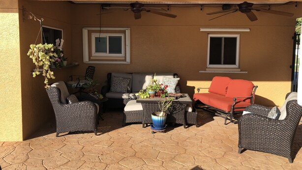 Eine Terrasse im Freien mit Korbmöbeln, einem roten Sofa und Topfpflanzen.